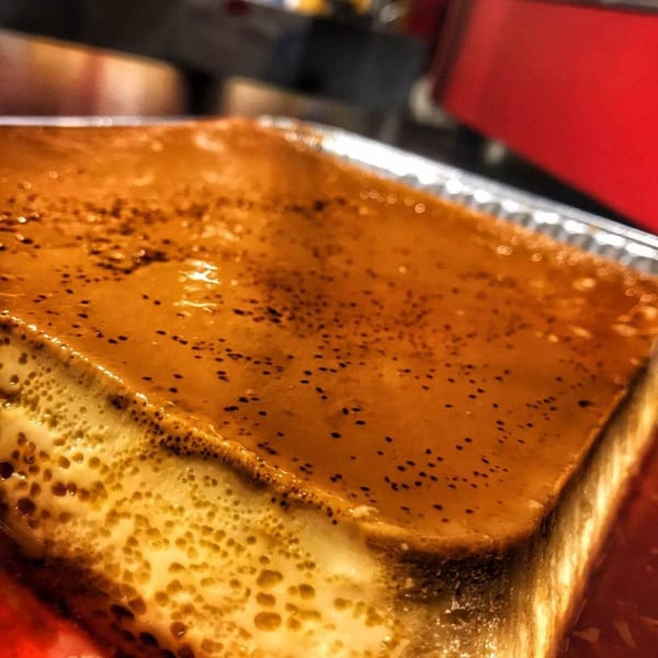 Close-up of a large, rectangular flan with a rich caramel topping and creamy custard base.