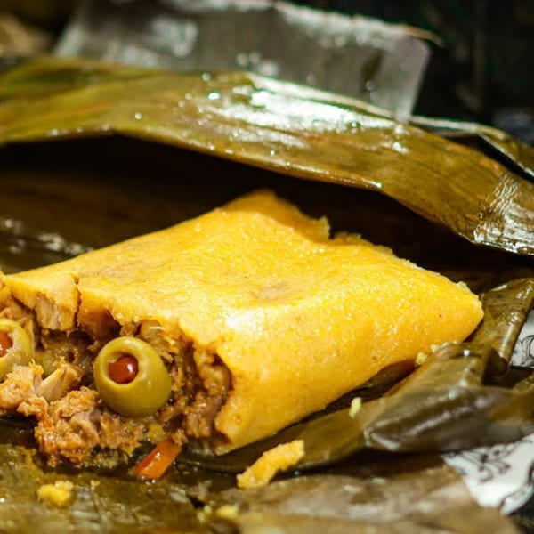 A Venezuelan hallaca, a corn dough dish filled with meat and olives, unwrapped from its plantain leaf.