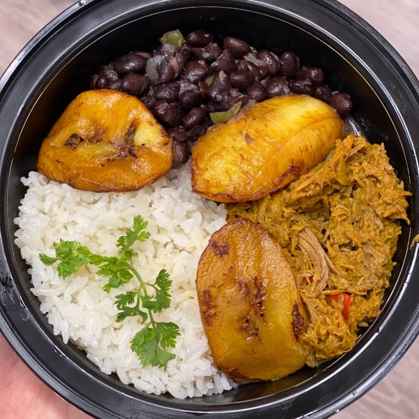 Sabrosa Venezuela's Latin-American dish with rice, black beans, plantains, and shredded meat in a black bowl.