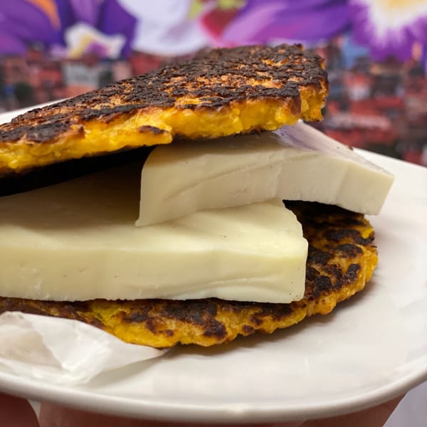 Close-up of a Sabrosa Venezuela cachapa, a golden corn pancake, filled with thick slices of white cheese.